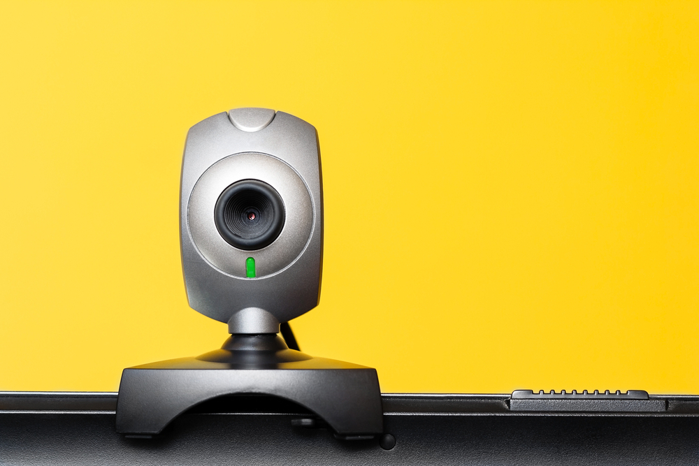 Best webcam with microphone in india placed above the laptop with yellow background